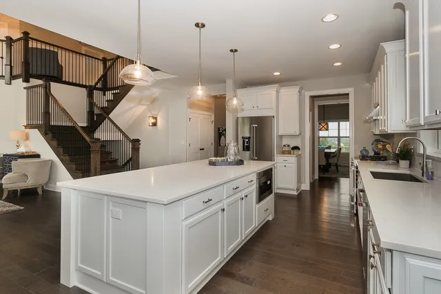 a large kitchen with lot of counter top space a sink a refrigerator and wooden floor