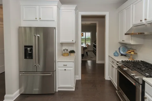 a kitchen with stainless steel appliances a refrigerator a stove and white cabinets