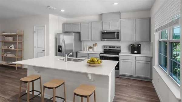 a kitchen with stainless steel appliances a sink a stove a table and chairs