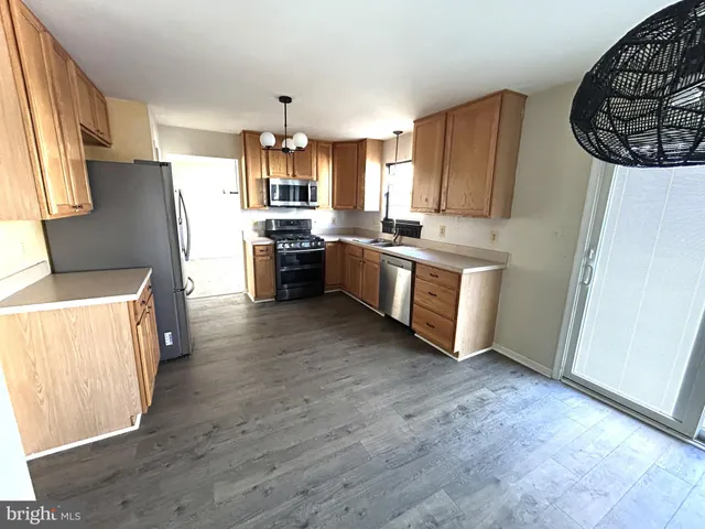 a large kitchen with a wooden floor and stainless steel appliances