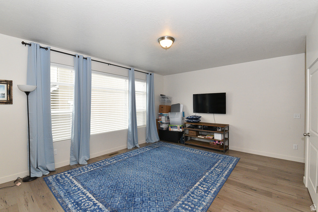 1632 North Apache Road Saratoga Springs, UT 84045 - Photo 4 of 28 Spacious room featuring wood-finish flooring, white walls, and a series of three windows with horizontal blinds