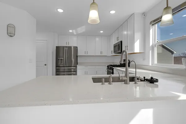 a kitchen with stainless steel appliances granite countertop a sink and a refrigerator