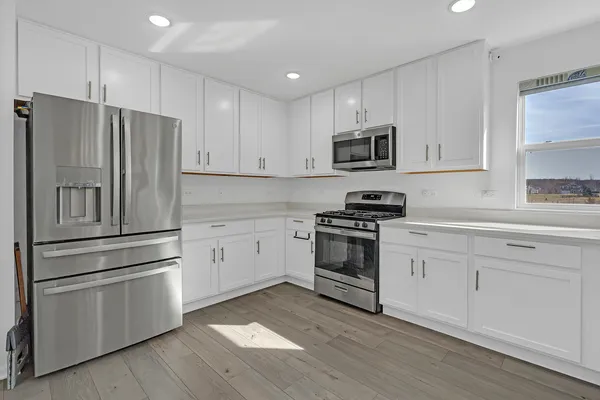 a kitchen with cabinets stainless steel appliances and wooden floor
