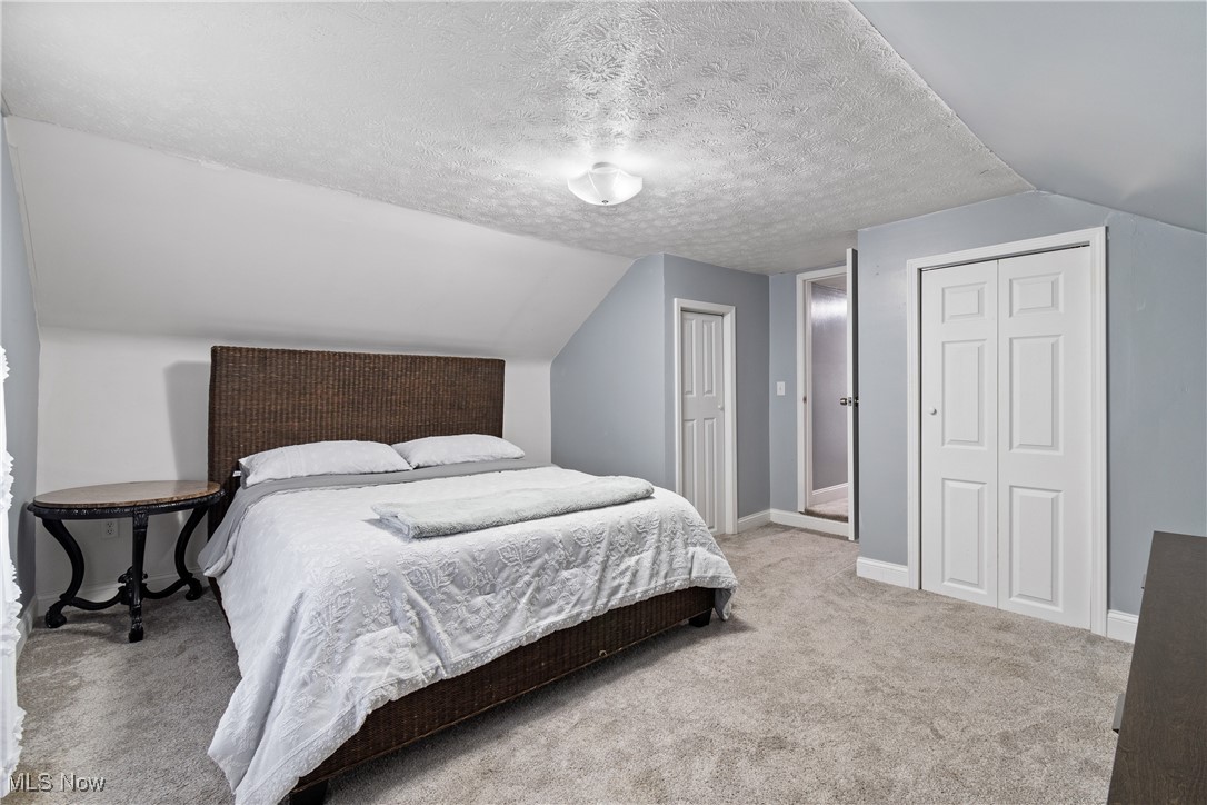 4786 Mayfair Road North Canton, OH 44720 - Photo 19 of 38 Bedroom featuring a textured ceiling, light carpet, lofted ceiling, and a closet