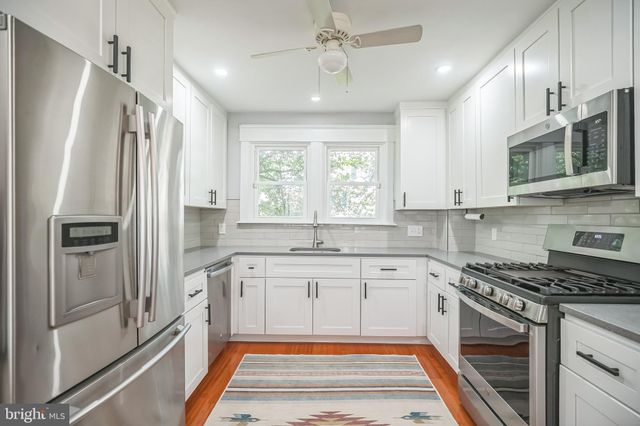 a kitchen with stainless steel appliances granite countertop a refrigerator a sink dishwasher a dining table and chairs with wooden floor