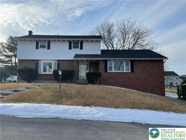 a front view of a house with a yard covered in snow