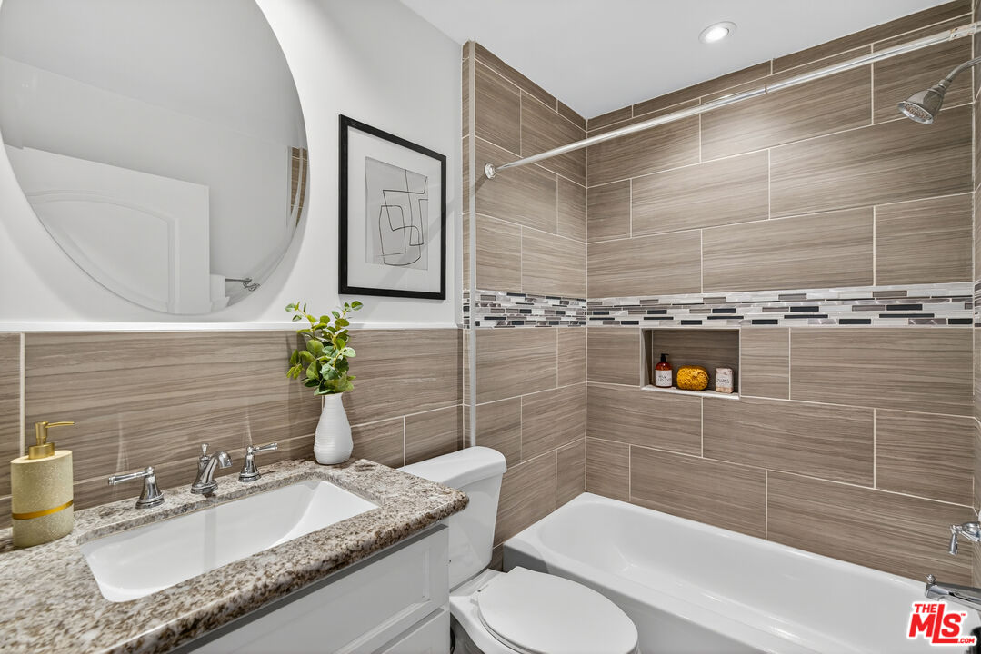 1125 Pico Boulevard, Unit 103 Santa Monica, CA 90405 - Photo 18 of 33 a bathroom with a granite countertop sink toilet and shower