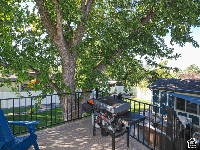 3308 Willow Ridge Road Salt Lake City, UT 84121 - Photo 14 of 59 Expansive wood-finish deck with black metal railings, mature trees, and a manicured lawn