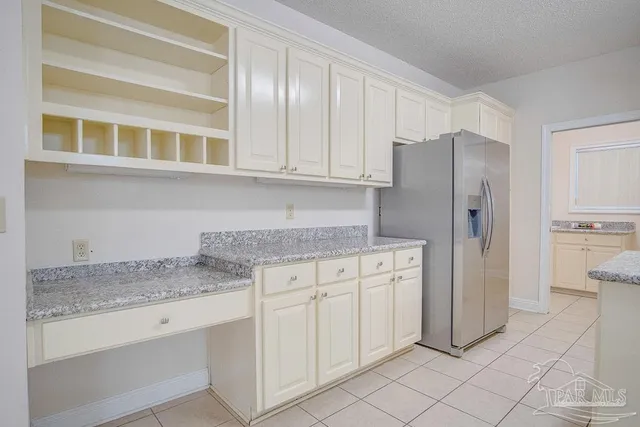 a kitchen with stainless steel appliances granite countertop a refrigerator and white cabinets