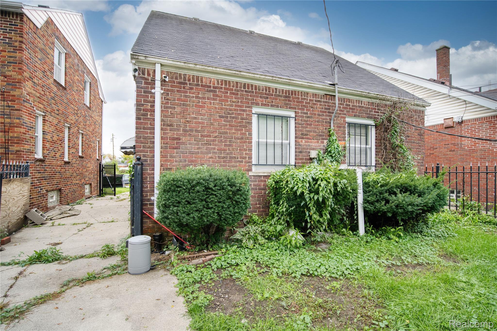 13644 Castleton Street Detroit, MI 48227 - Photo 18 of 18 Brick exterior with security bars on windows, concrete driveway, and partial fencing