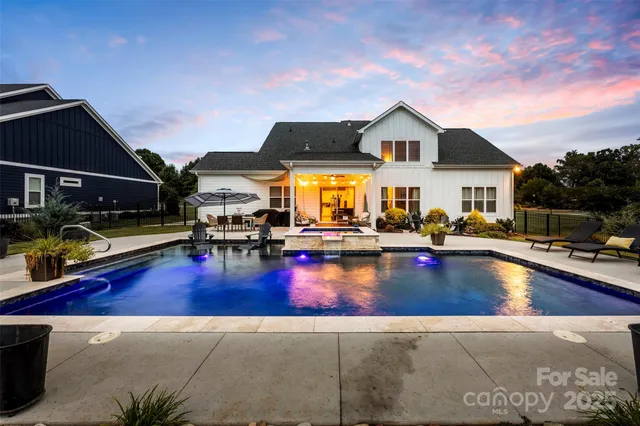 a view of swimming pool with outdoor seating and house in the background