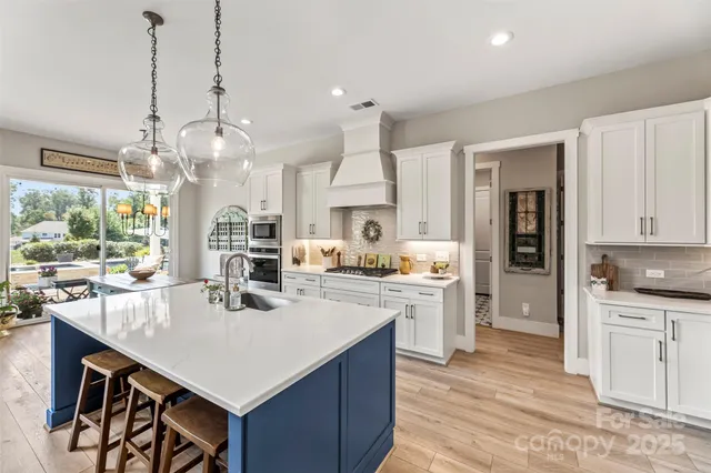 a kitchen with a stove a refrigerator a sink dishwasher and white cabinets with wooden floor