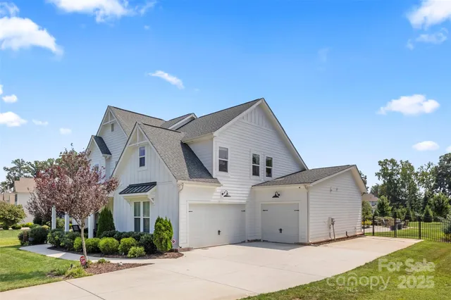 a view of a white house with a big yard and large trees