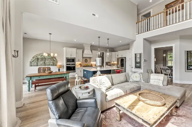 a living room with furniture kitchen view and a chandelier