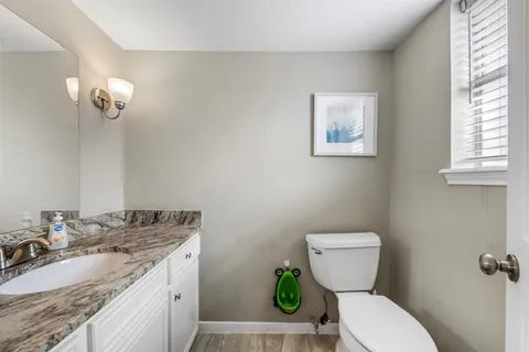 a bathroom with a granite countertop toilet sink and mirror