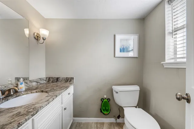 a bathroom with a granite countertop toilet sink and mirror