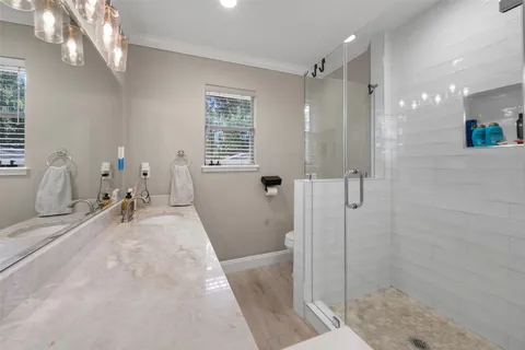 a bathroom with a tub a window and glass door shower