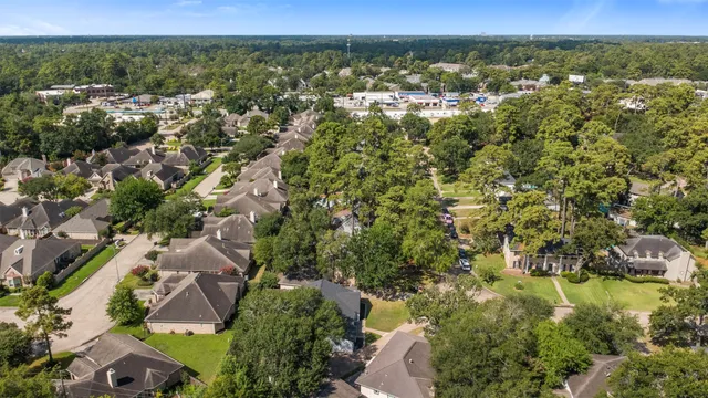 an aerial view of residential houses with outdoor space and trees