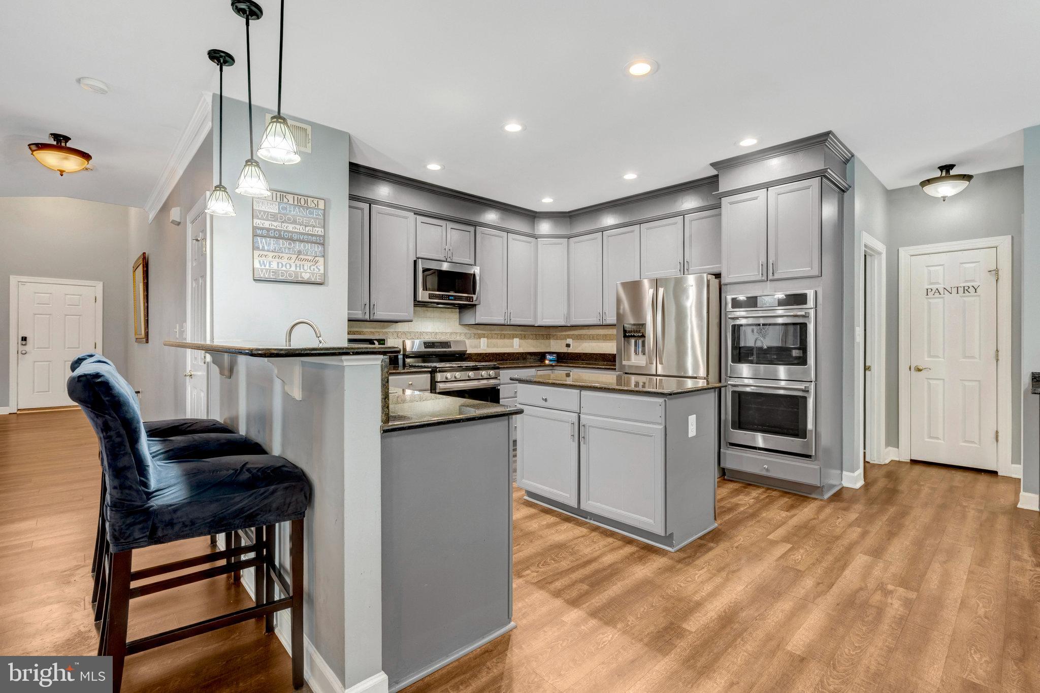 4169 Agency Loop Triangle, VA 22172 - Photo 10 of 56 a kitchen with stainless steel appliances kitchen island granite countertop a refrigerator a stove and a sink with wooden floor