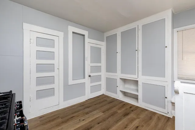 a view of an empty room with wooden floor and closet