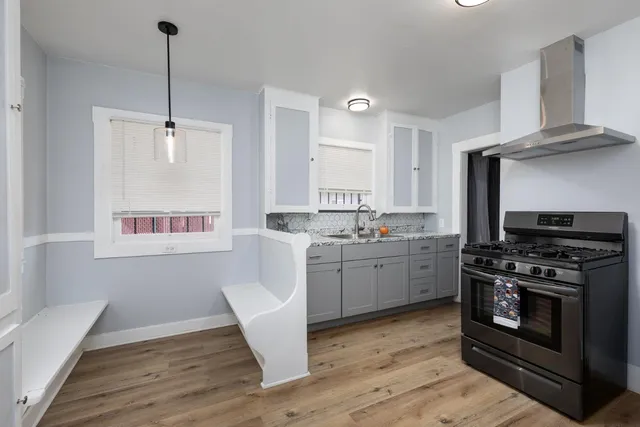 a kitchen with a stove a sink and a wooden floor