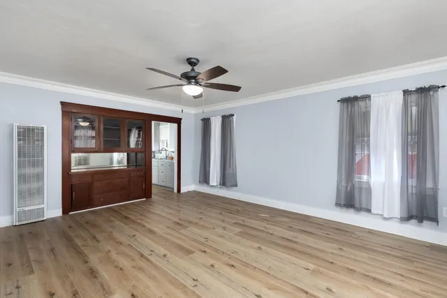a view of an empty room with wooden floor and a window
