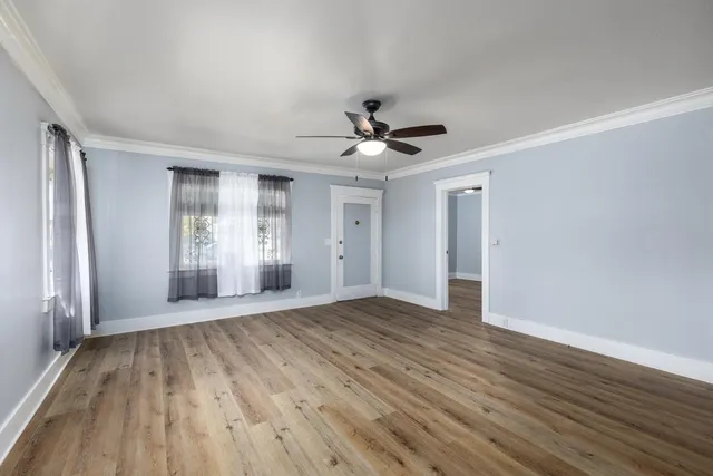 a view of an empty room with window and wooden floor