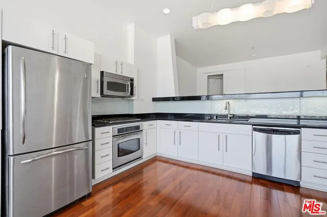 a kitchen with granite countertop stainless steel appliances a refrigerator a sink and cabinets