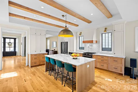 a kitchen with stainless steel appliances granite countertop a stove a sink dishwasher and a dining table with wooden floor