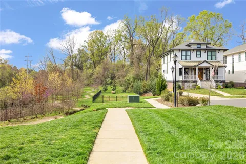 a view of a fountain in front of a house with a big yard and large trees