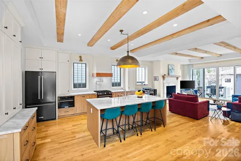 a view of a kitchen with kitchen island granite countertop a refrigerator a stove a dining table and chairs with wooden floor