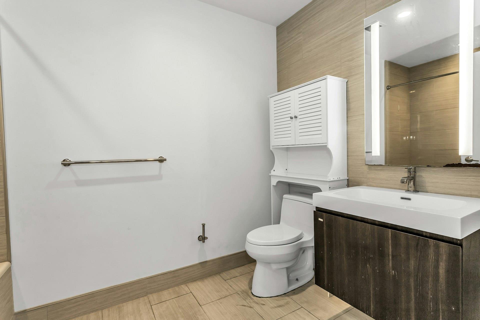 131-03 40 Road, Unit 10E Queens, NY 11354 - Photo 11 of 15 a bathroom with a sink a toilet and a mirror