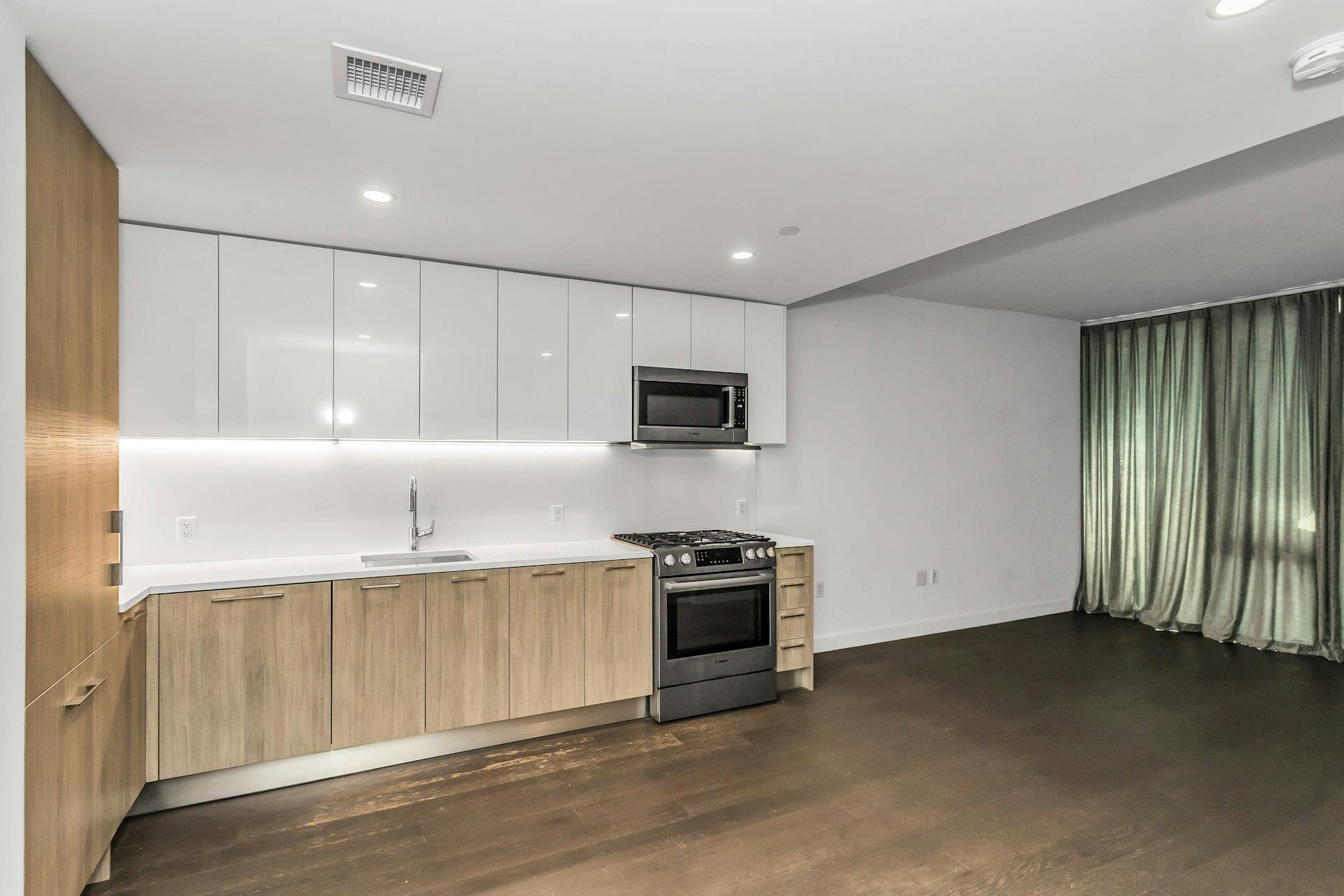 131-03 40 Road, Unit 10E Queens, NY 11354 - Photo 6 of 15 a kitchen with stainless steel appliances granite countertop a stove a sink and a microwave