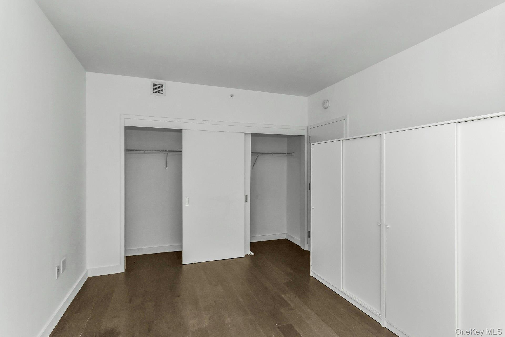 131-03 40 Road, Unit 10E Queens, NY 11354 - Photo 10 of 15 Unfurnished bedroom featuring wood finished floors and multiple closets