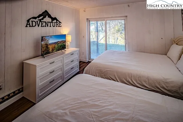 a bedroom with a bed and a flat tv screen on dresser