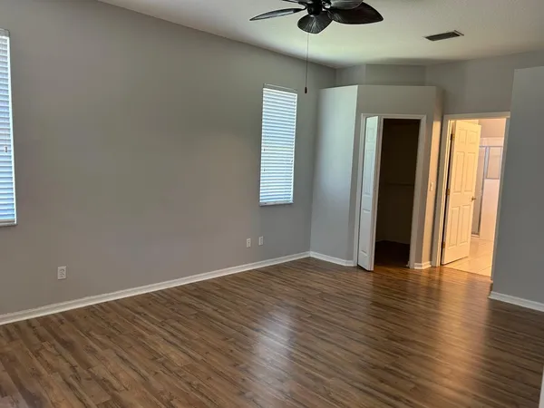 an empty room with wooden floor and windows