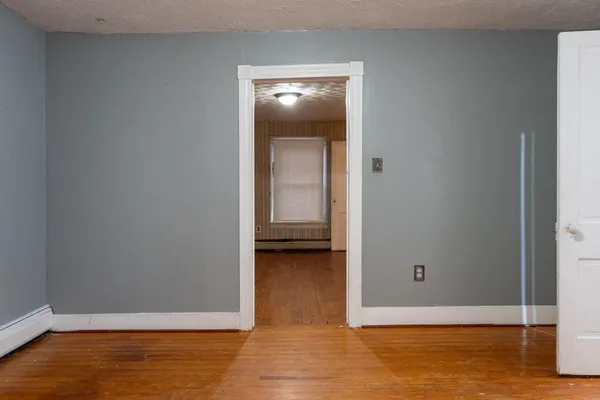 an empty room with wooden floor cabinet and windows