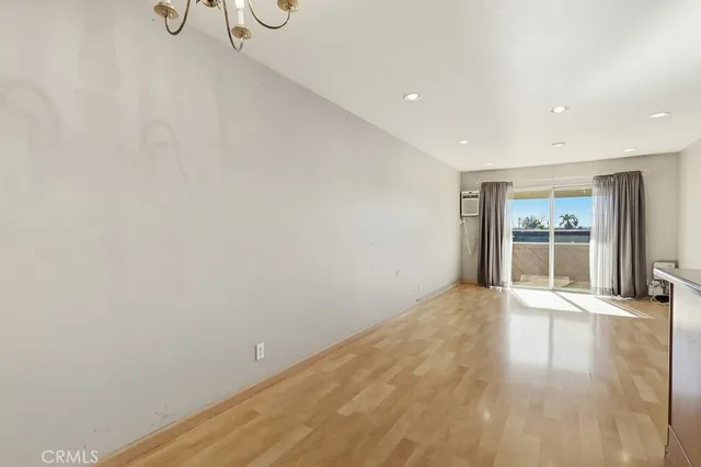 a view of an empty room with wooden floor and windows