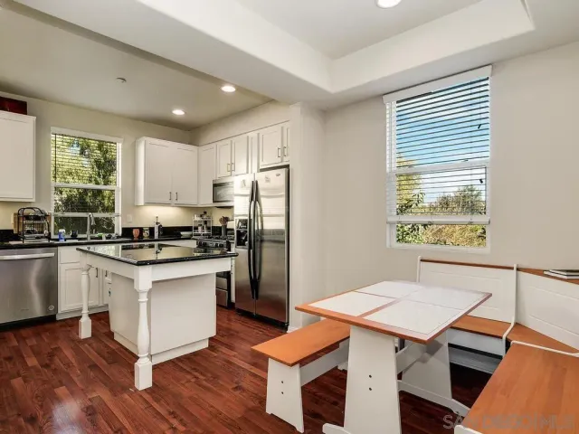 a kitchen with stainless steel appliances granite countertop a stove a sink dishwasher a refrigerator and white countertops with wooden floor