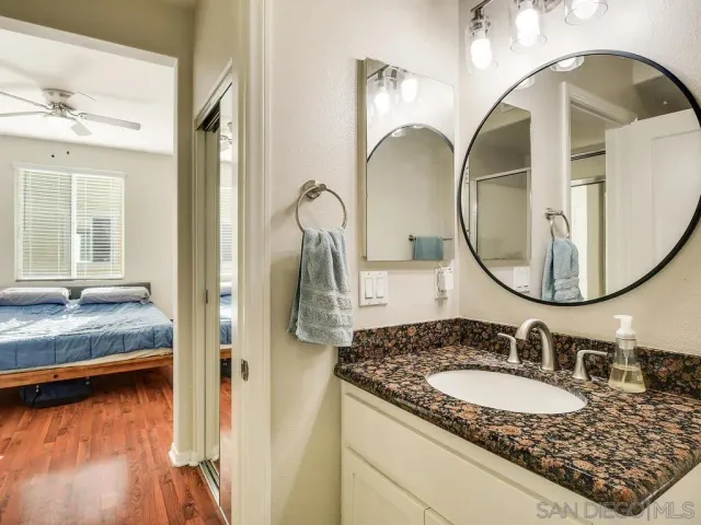 a en suite bathroom with a granite countertop sink and a mirror