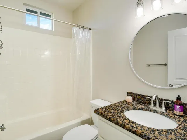 a bathroom with a granite countertop sink toilet and a mirror