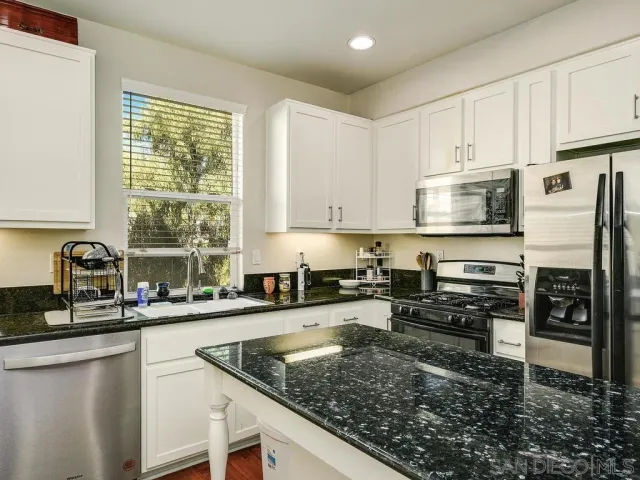 a kitchen with stainless steel appliances granite countertop a stove sink and cabinets