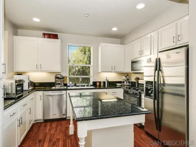 a kitchen with a refrigerator a stove a sink and cabinets