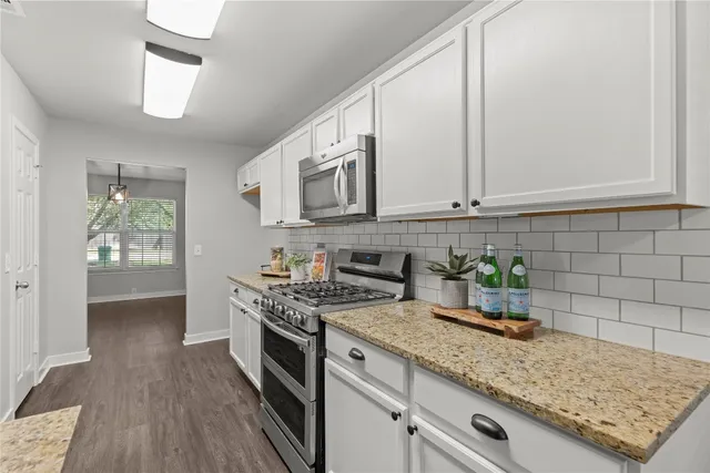 a bathroom with a granite countertop sink a toilet a mirror and shower