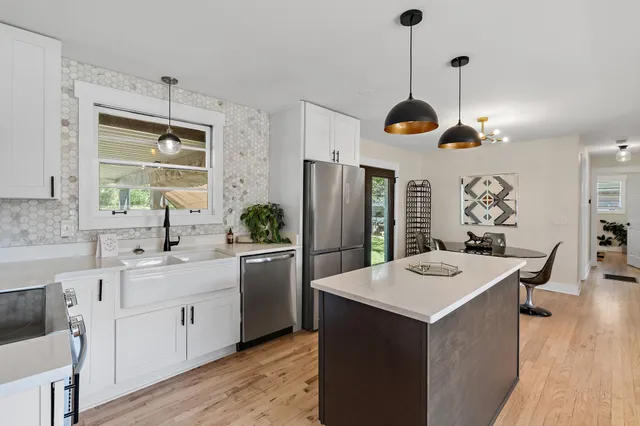 a kitchen with a sink a center island cabinets and stainless steel appliances