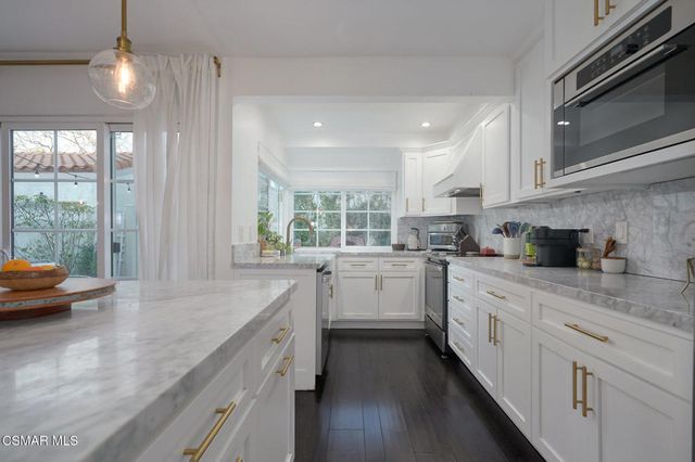 a kitchen with white cabinets and wooden floor