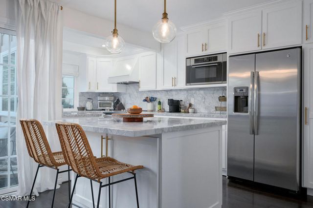 a kitchen with stainless steel appliances granite countertop a refrigerator a sink a stove a dining table and chairs