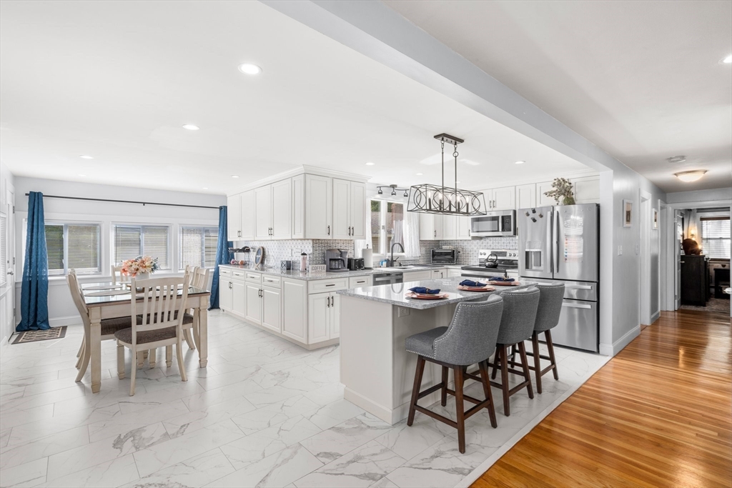 a dining hall with stainless steel appliances kitchen island granite countertop a dining table chairs and view kitchen