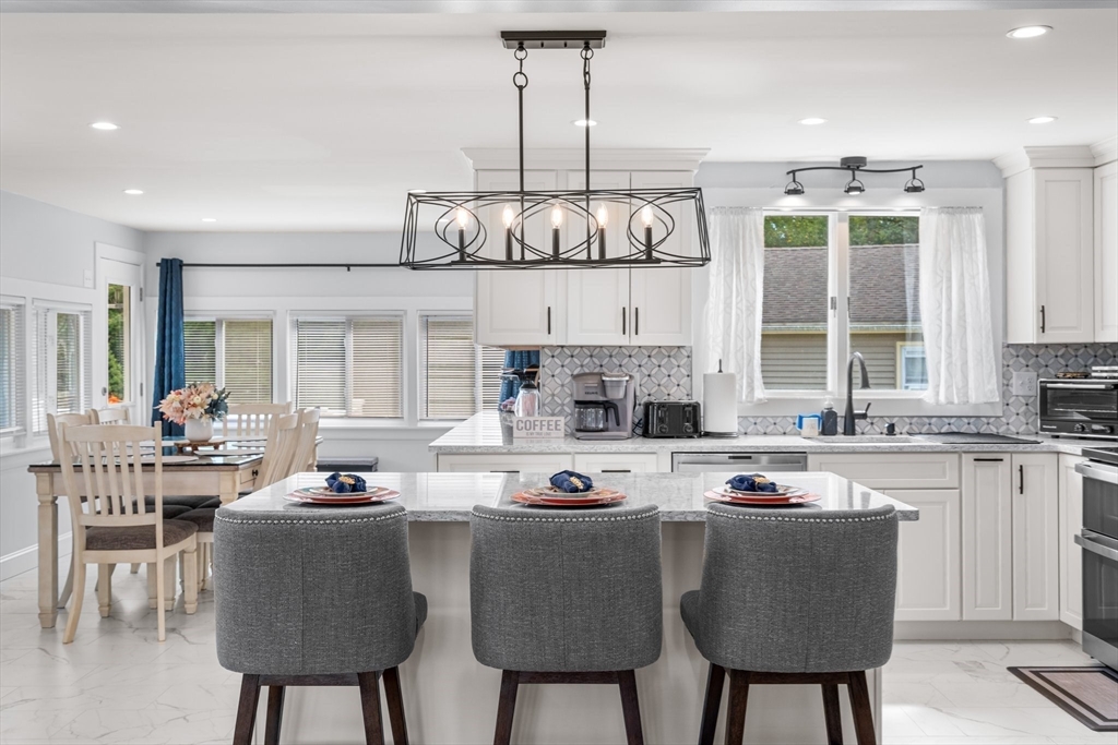 5 Albert Road Peabody, MA 01960 - Photo 5 of 39 a kitchen with stainless steel appliances granite countertop a stove a sink dishwasher a dining table and chairs with wooden floor