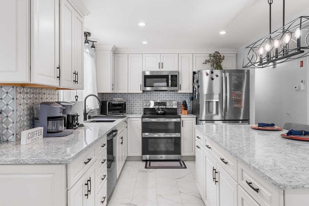 5 Albert Road Peabody, MA 01960 - Photo 7 of 39 a kitchen with granite countertop a refrigerator a sink and white cabinets